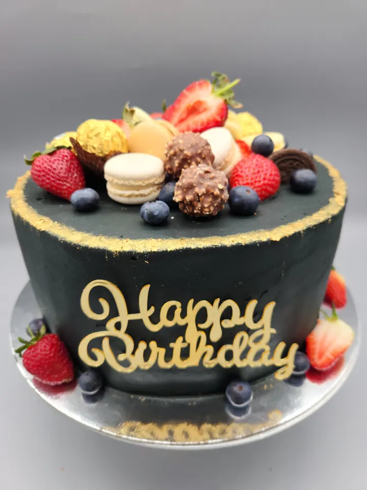 Black Happy Birthday cake with fresh fruit and macarons