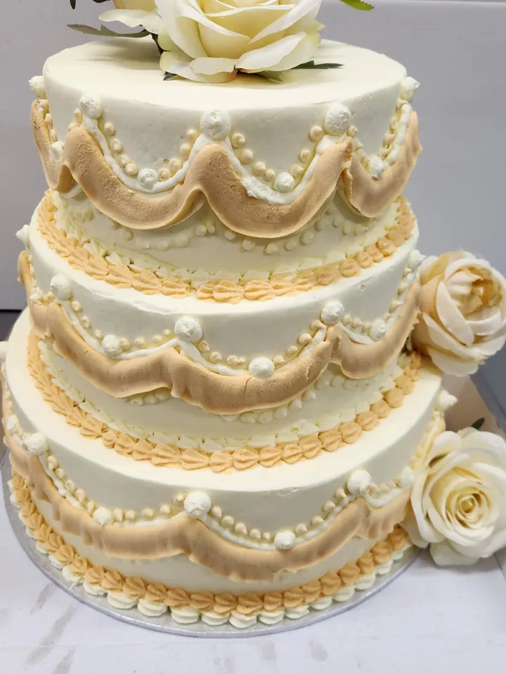Three-tier ivory wedding cake with piped detail